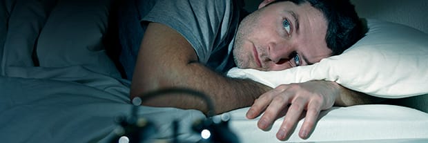 man in bed struggling to fall asleep