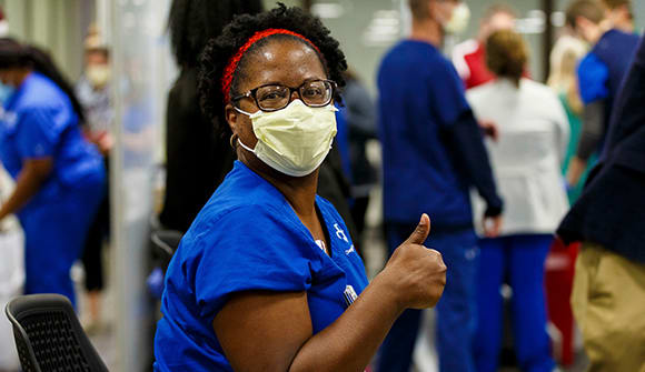 Baptist healthcare professional getting COVID-19 vaccine with a thumbs up