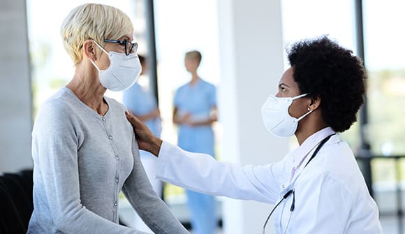 A physician and patient are sitting down looking at one another in a hospital lobby.