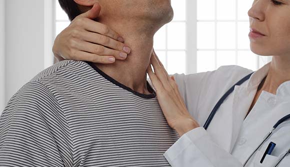 Female physician checking for a lump in man's neck