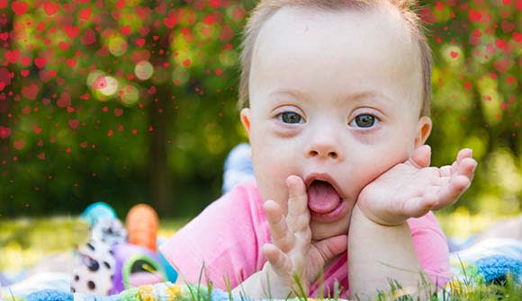 baby laying on a mat the grass with red hearts overlayed on the image