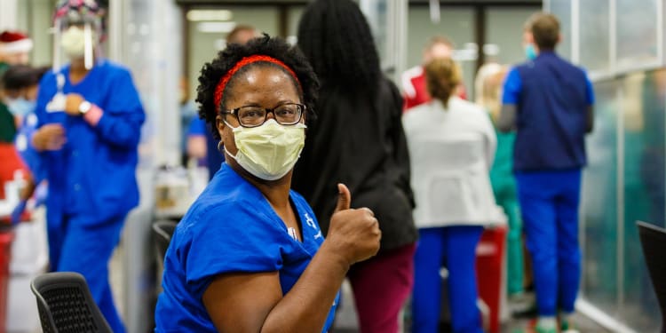 nurse manager receives covid vaccine and gives thumbs up