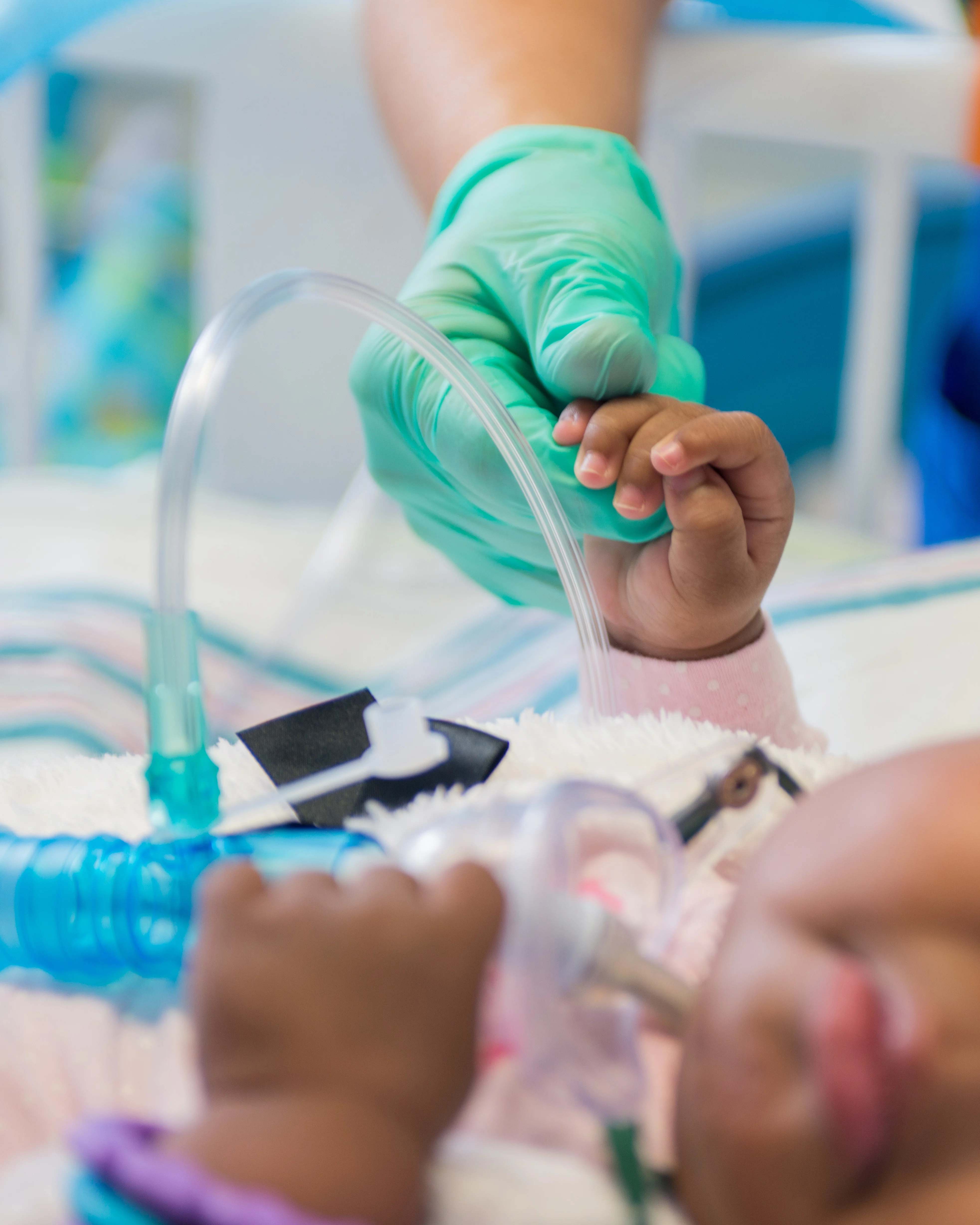 close up of infant girl in the PICU holding the hand of a nurse