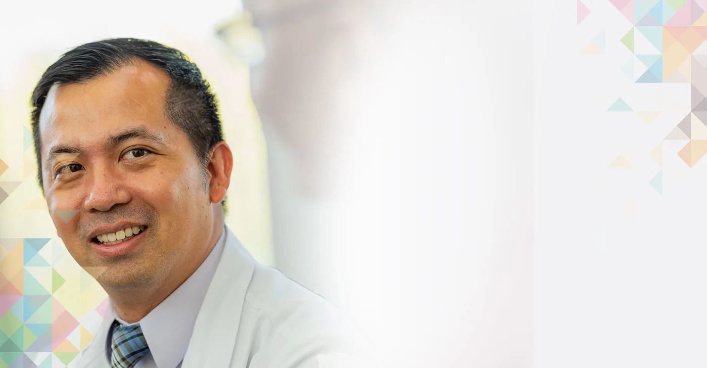 a smiling Dr. Jon Vu, medical oncologist, sits next to a patient.