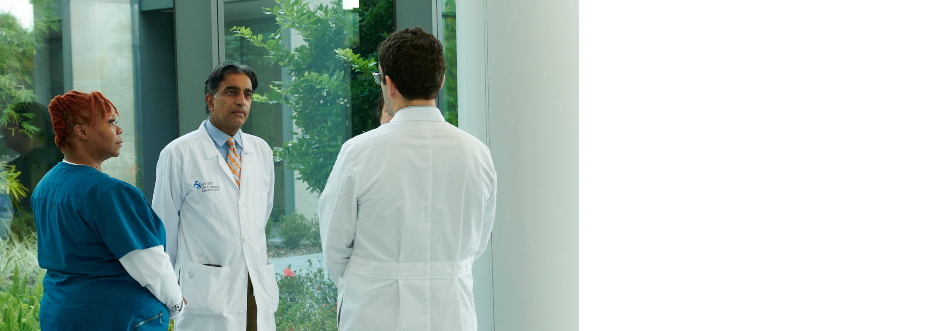 group of doctors talking with one another in front of a window