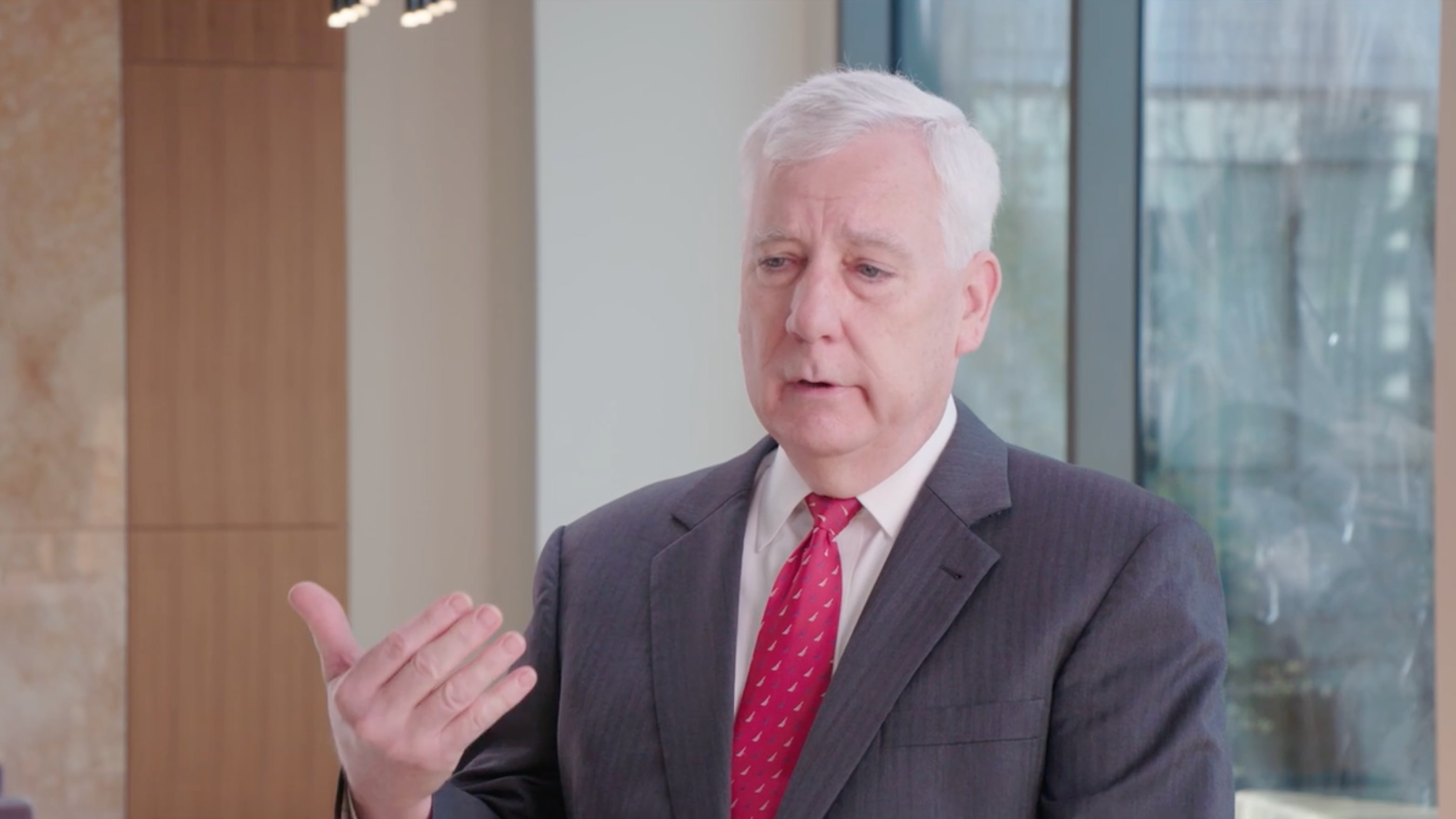 Dr. Putnam in a suit and tie using his hands to explain something