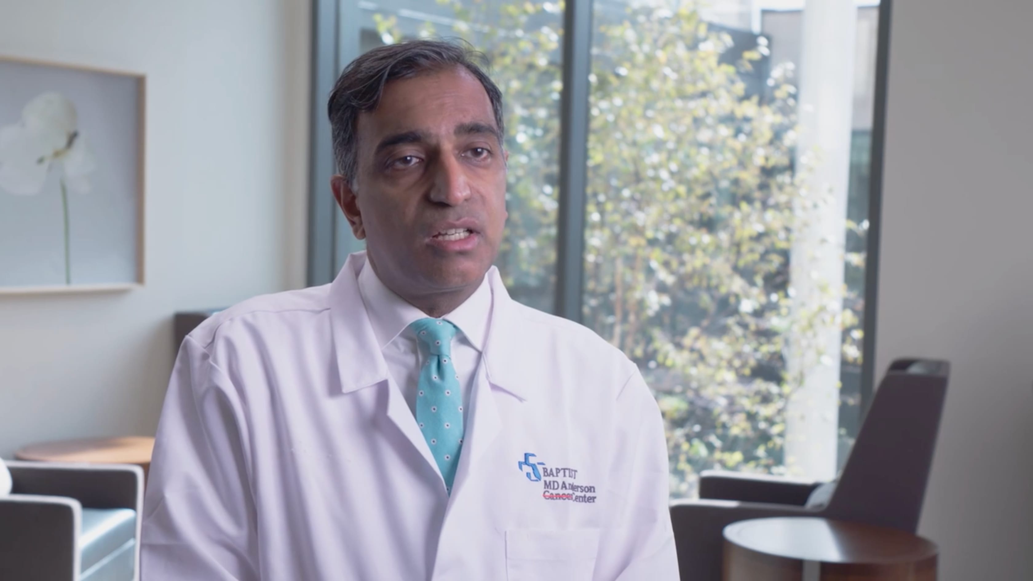 Doctor in a white BMDA coat sitting in front of a bright window