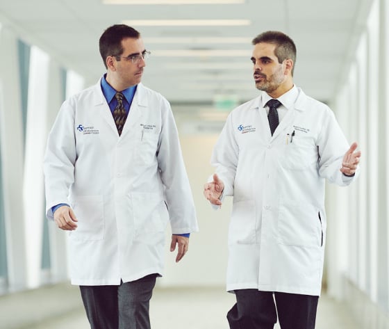 Dr. Cavaliere and Dr. Olsen talk as they walk down the hallway.