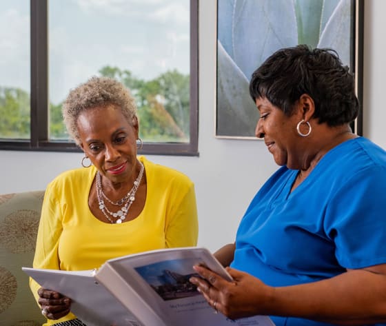 A female Baptist MD Anderson breast cancer nurse navigator goes through the patient binder with a senior female patient.