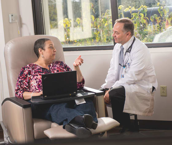 Dr. Zaiden sits with a female patient in a treatment room.