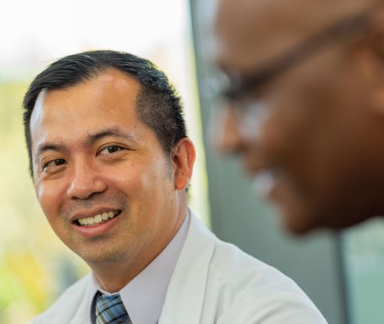 Dr. Vu sits, smiling, towards a male patient.