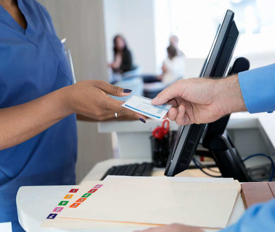 Closeup of male patient handing a card to a female healthcare professional.