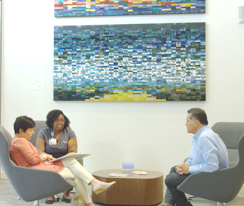 A nurse navigator walks through the patient binder with a wife and husband in the Baptist MD Anderson lobby.