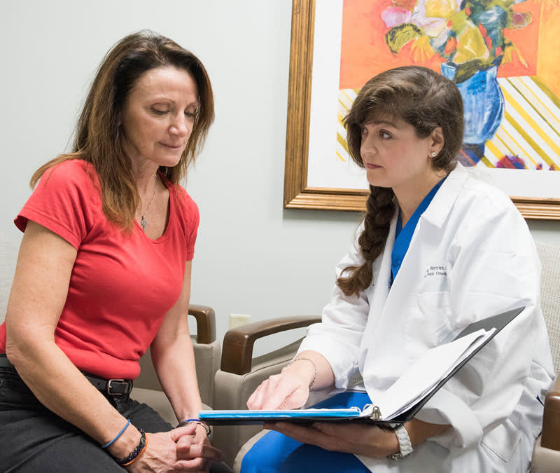 A female physician goes through the Baptist MD Anderson patient binder with a female patient.