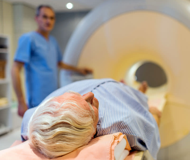 A senior patient lays at the entrance of an MRI machine.