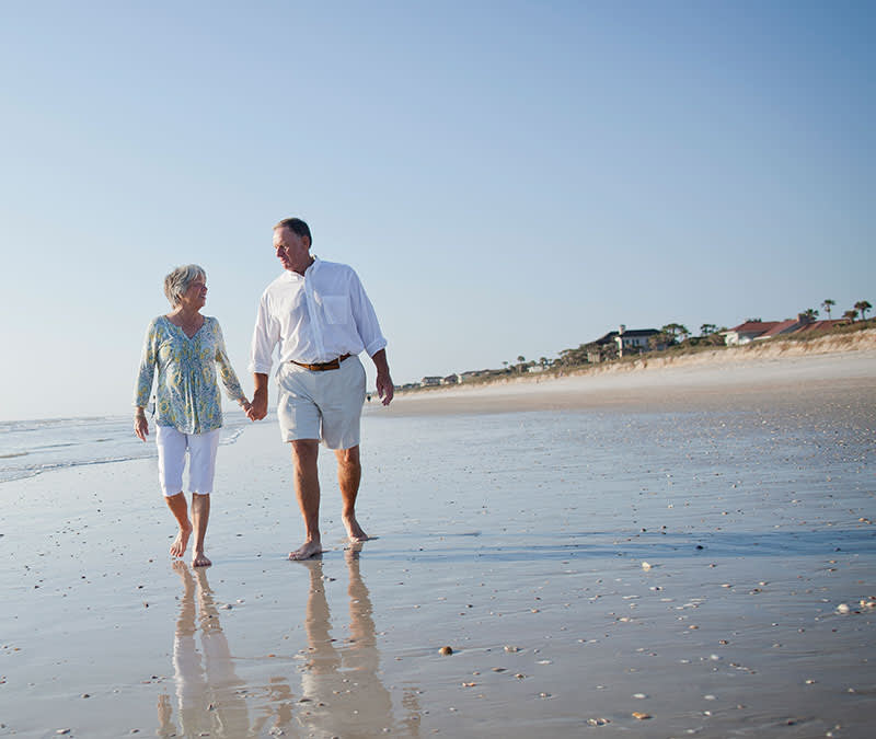A senior couple walk along Jacksonville beach.