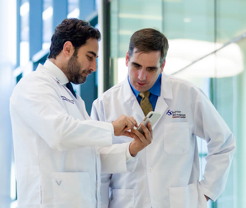 Two male physicians review information together on an iPhone.