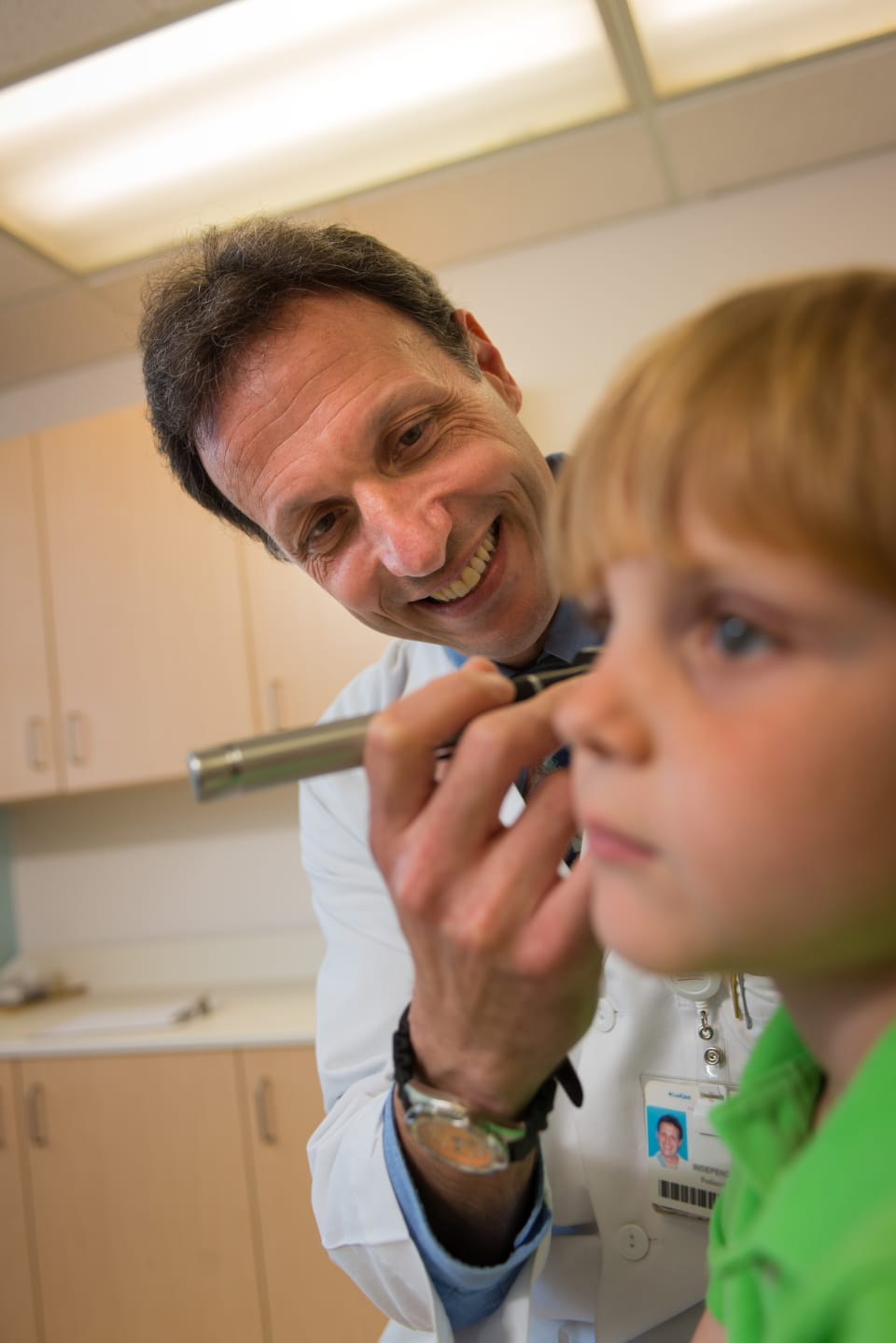 ENT specialist at Wolfson Children's checkin a young boy's ear with a light