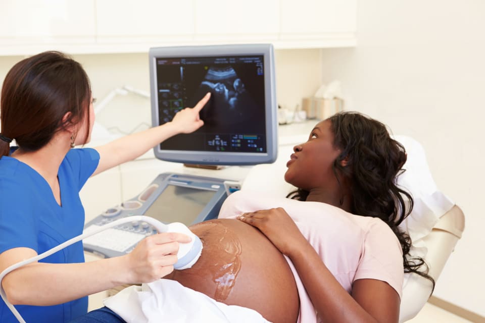 pregnant woman having an ultrasound scan done by a medical professional