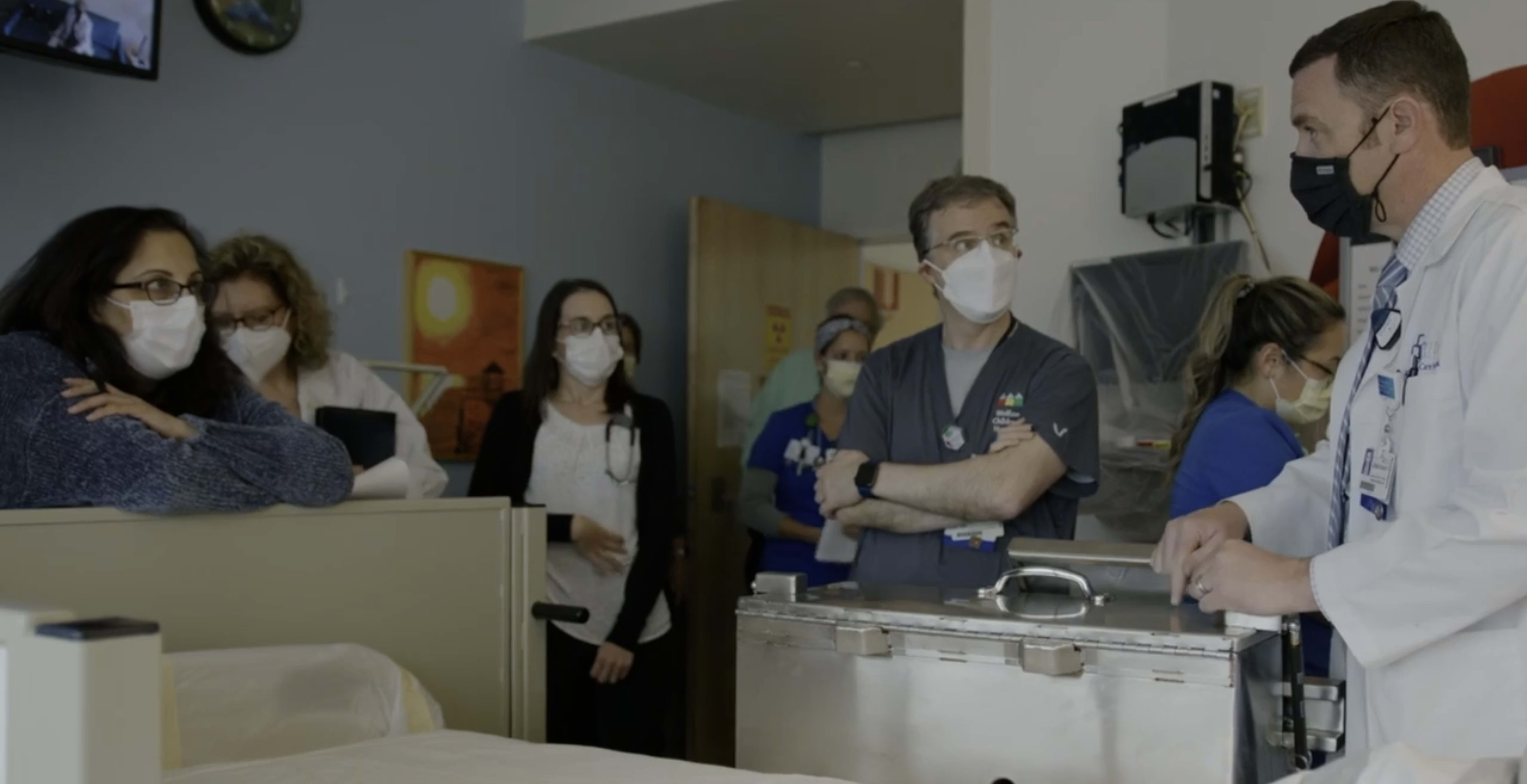 a group of providers huddle in the MIBG patient room to discuss treatments.