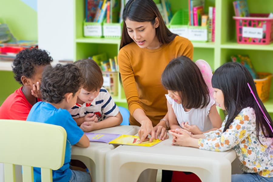 Photos of a classroom setting with a diverse group of young children sitting around a table while the teacher reads from a book