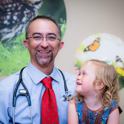 Small girl smiling up at her doctor