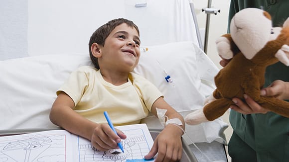 boy coloring in hospital bed