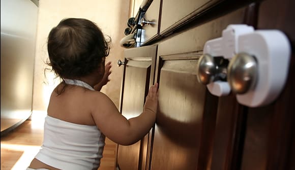 A baby investigates cabinets with baby locks.