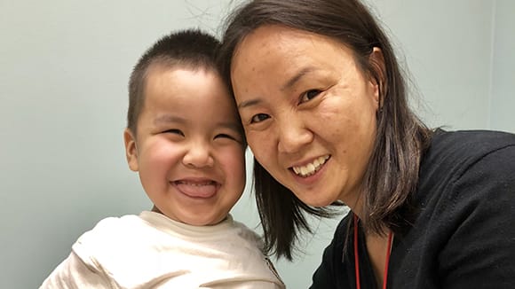 A young boy and his mother smile.