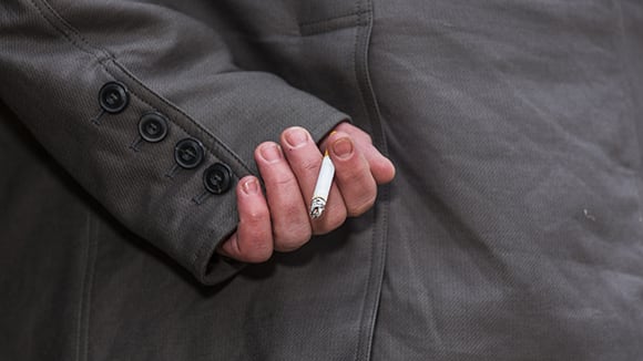 Man with cigarette hidden behind his back