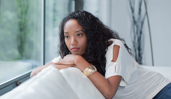 Young woman on couch looking pensive