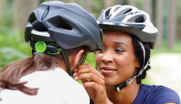 mom fastening helmet on child