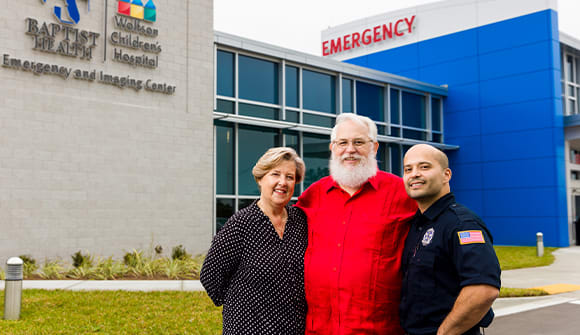 Patient Jim Markert standing next to his wife Timmi and Luis Vargas, the security guard who administered CPR and helped save his life.