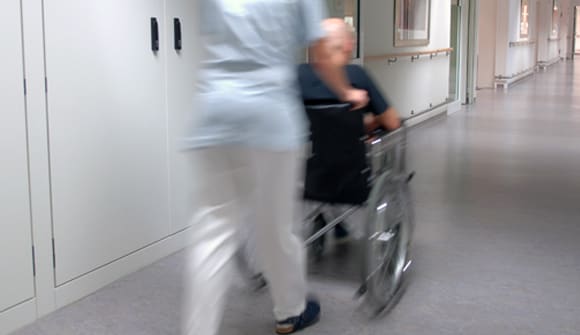 A nurse transports a patient in a wheelchair.