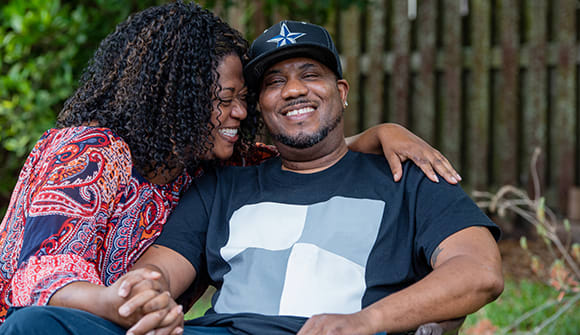 Man and wife share a laugh outdoors.