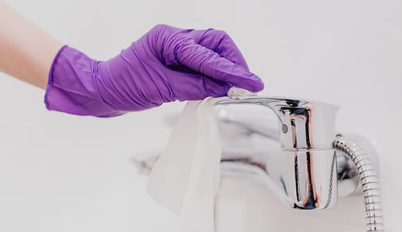 Hand in medical glove cleaning a sink