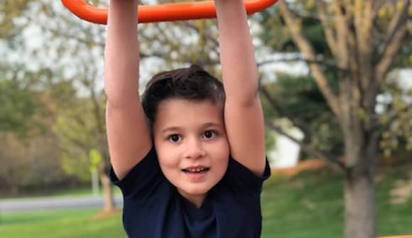 young boy swinging on monkey bars