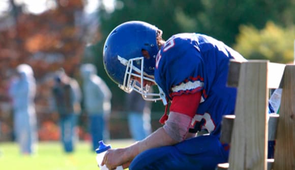 Football player on the bench holding a water bottle.