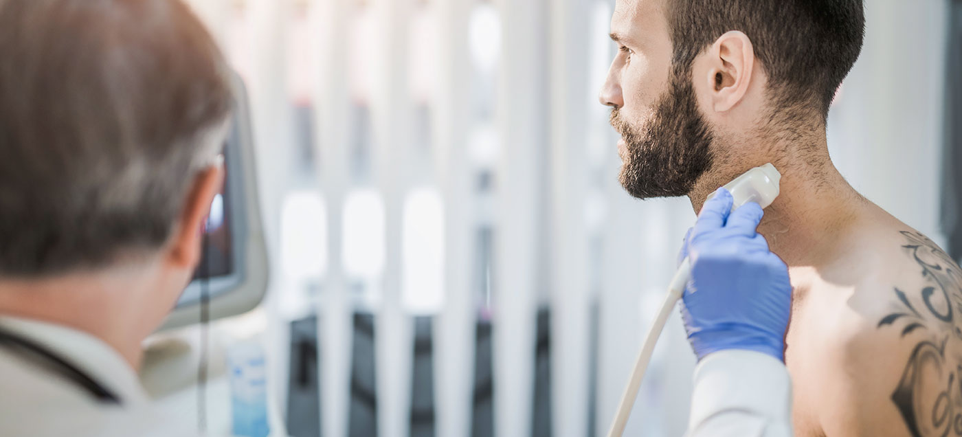 A physician scans a male patient's neck.