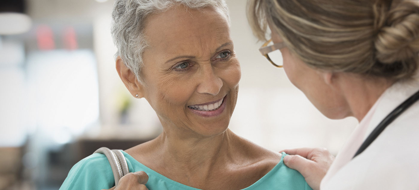 a female care team member encourages senior, female patient.