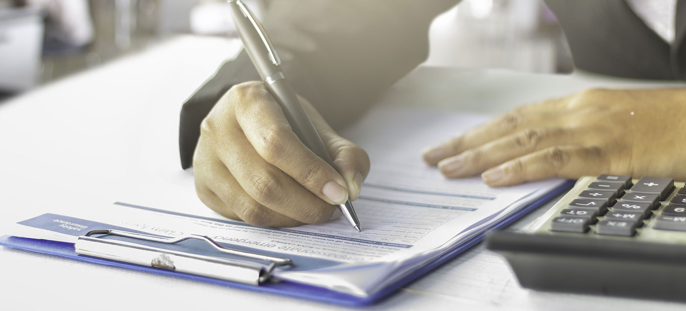 A closeup of hands, one with a pen, filling out a form on a clipboard.