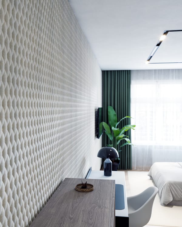 Modern interior room featuring a wall covered with Zintra Emboss Panel Tufted. The panels have a repeating, three-dimensional pattern creating a textured surface. The room includes a desk, chair, a plant, a television, and a bed in the background. Light from a window with sheer curtains illuminates the space.