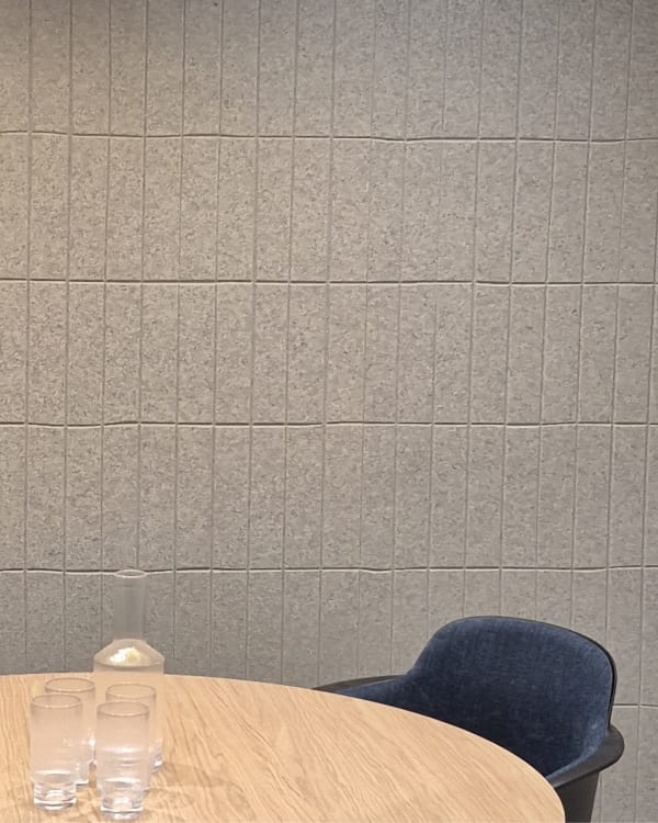 A modern meeting room in a corporate office, featuring a feature wall made from Zintra Organic Etch acoustic panels in the "Stacked Plain" design.