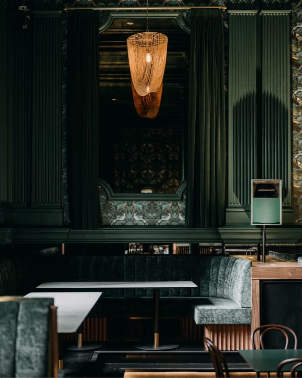 Interior view of Electra House in Adelaide featuring green upholstered banquette seating with Baresque Crypton Glamour fabric, paired with dark wood tables and chairs in a sophisticated, heritage-inspired setting.