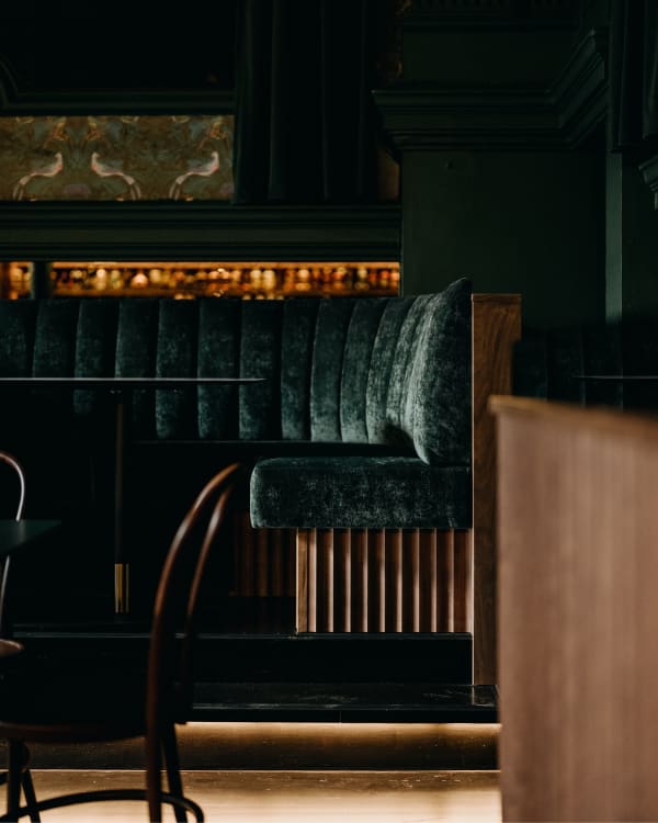 Interior view of Electra House in Adelaide featuring green upholstered banquette seating with Baresque Crypton Glamour fabric, paired with dark wood tables and chairs in a sophisticated, heritage-inspired setting.