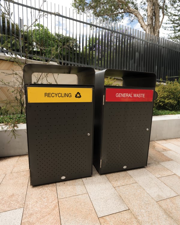 Close-up of the sleek, functional design of the botton+gardiner Bondi Single Bin Housings, featuring a perforated black finish and color-coded labels for effective waste separation.