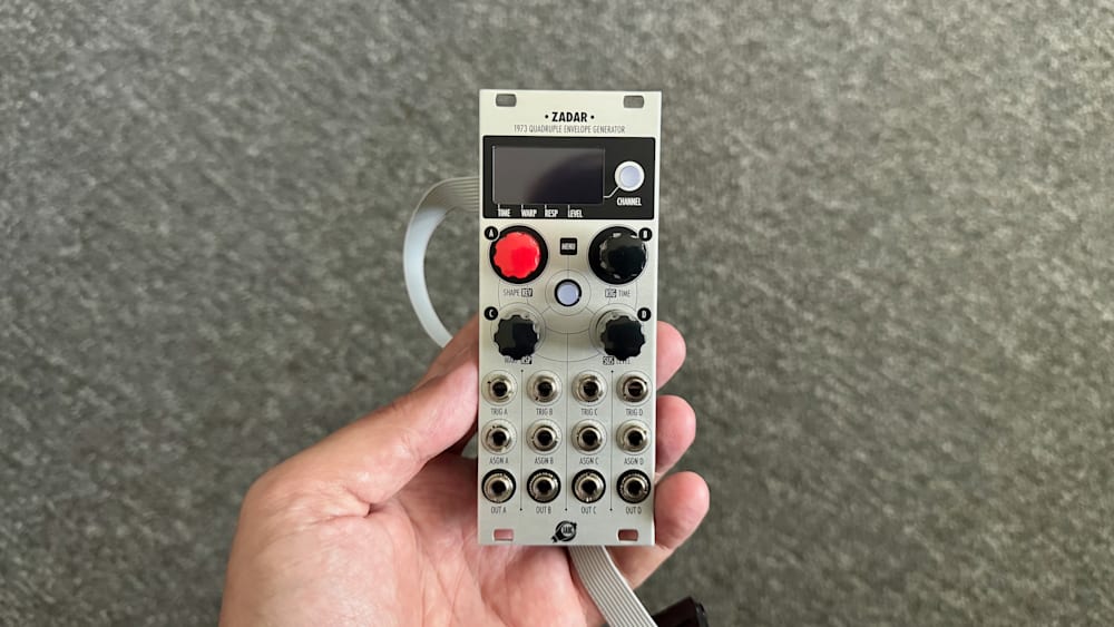 A white electronic device with several buttons is held in a hand.