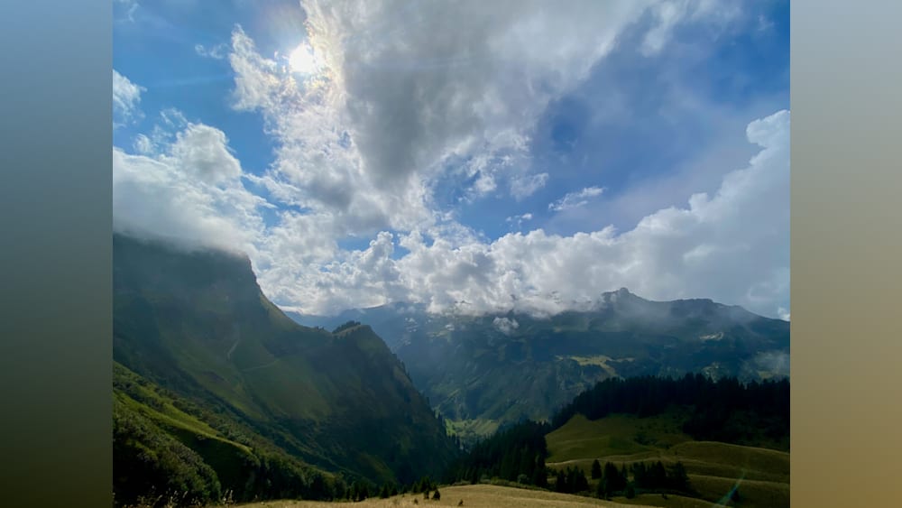 A mountain with clouds and a bright blue sky in the background.