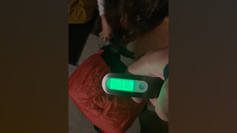 A person is holding a digital scale with their left hand and the number 728 is displayed.