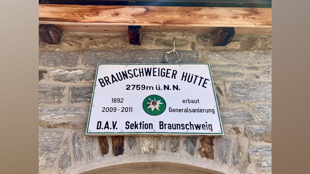 A sign written inGerman is displayed on a stone wall.